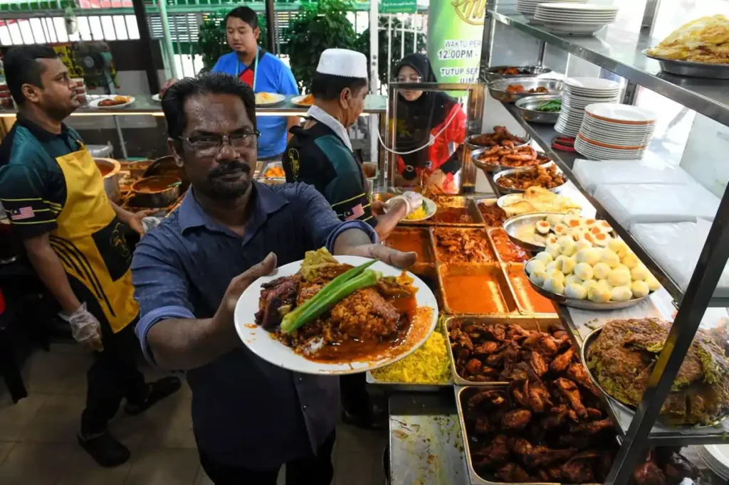 Nasi Kandar adalah hidangan khas Penang yang terdiri dari nasi putih yang disajikan dengan berbagai lauk seperti kari ikan, ayam goreng, dan telur rebus. Hidangan ini terkenal karena bumbu rempah yang kaya.